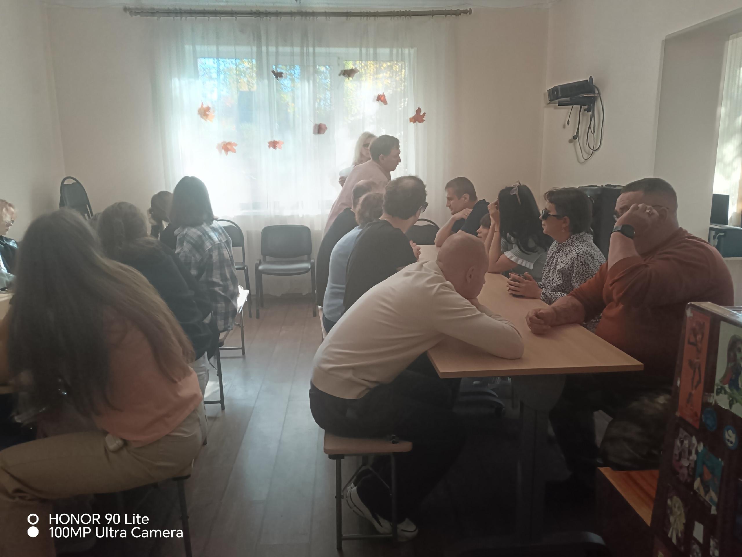 Участники встречи сидят за столами в светлой комнате