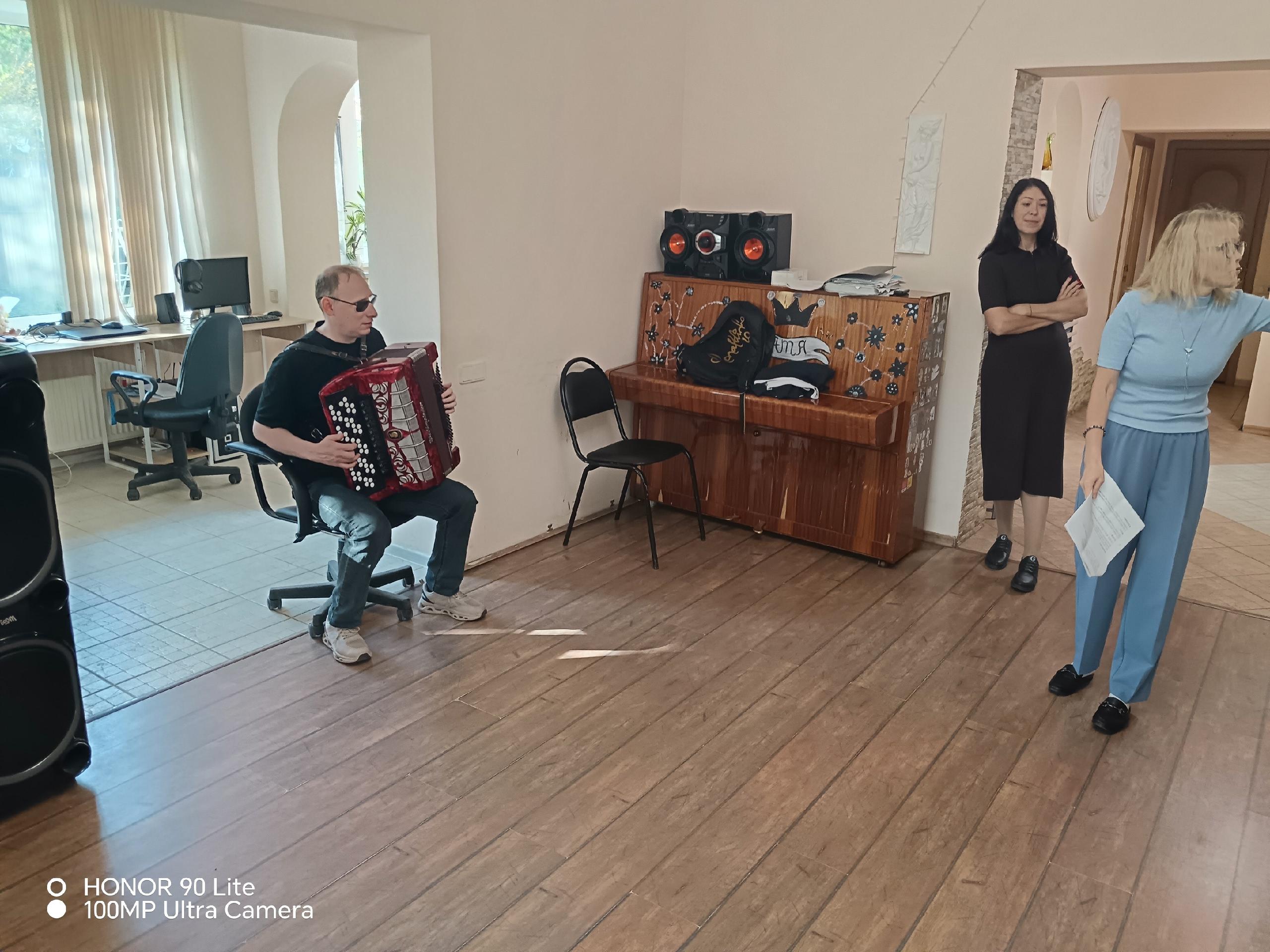 Мужчина в тёмных очках играет на красном баяне