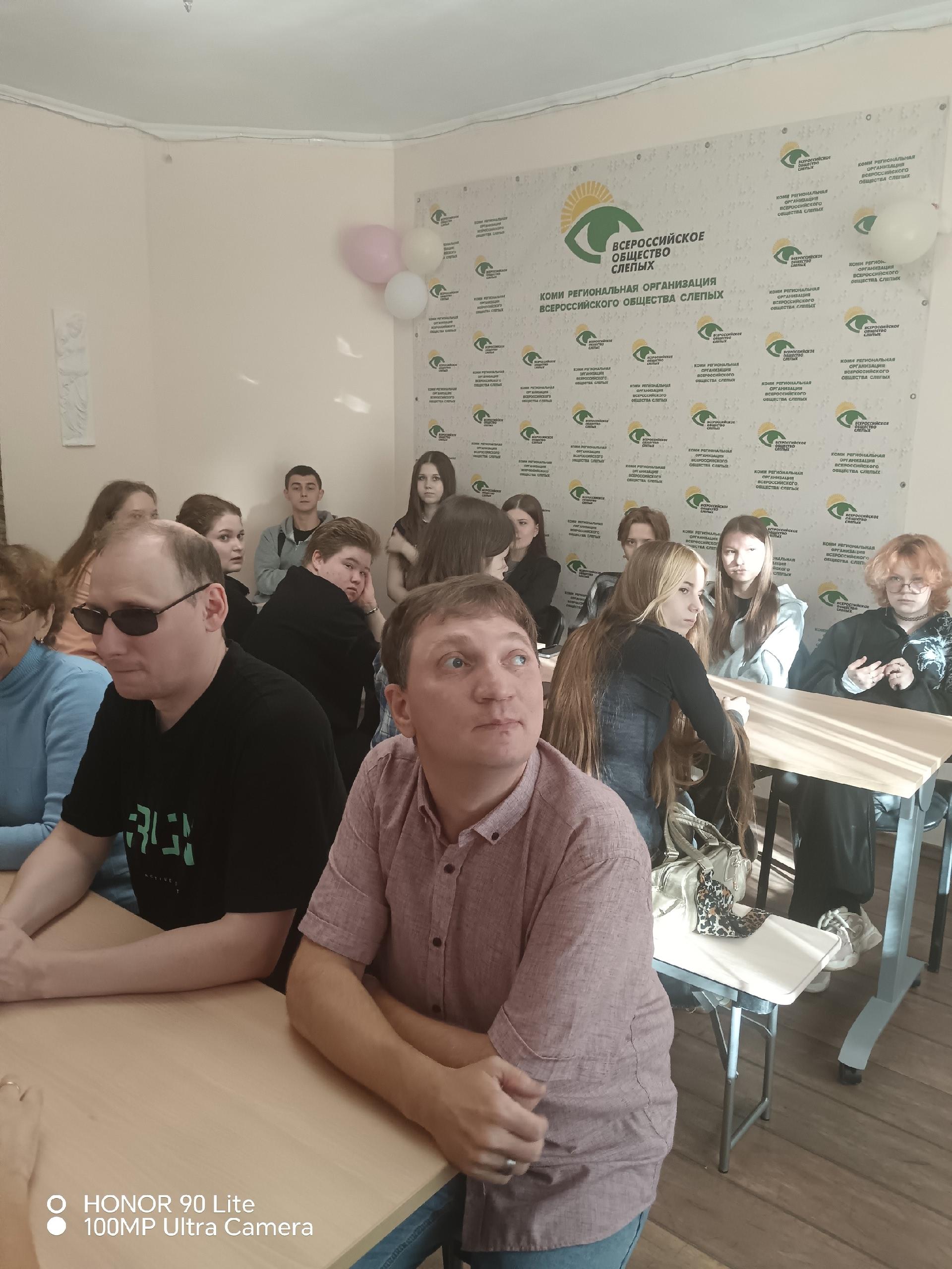 Мужчины и женщины внимательно слушают ведущего в помещении