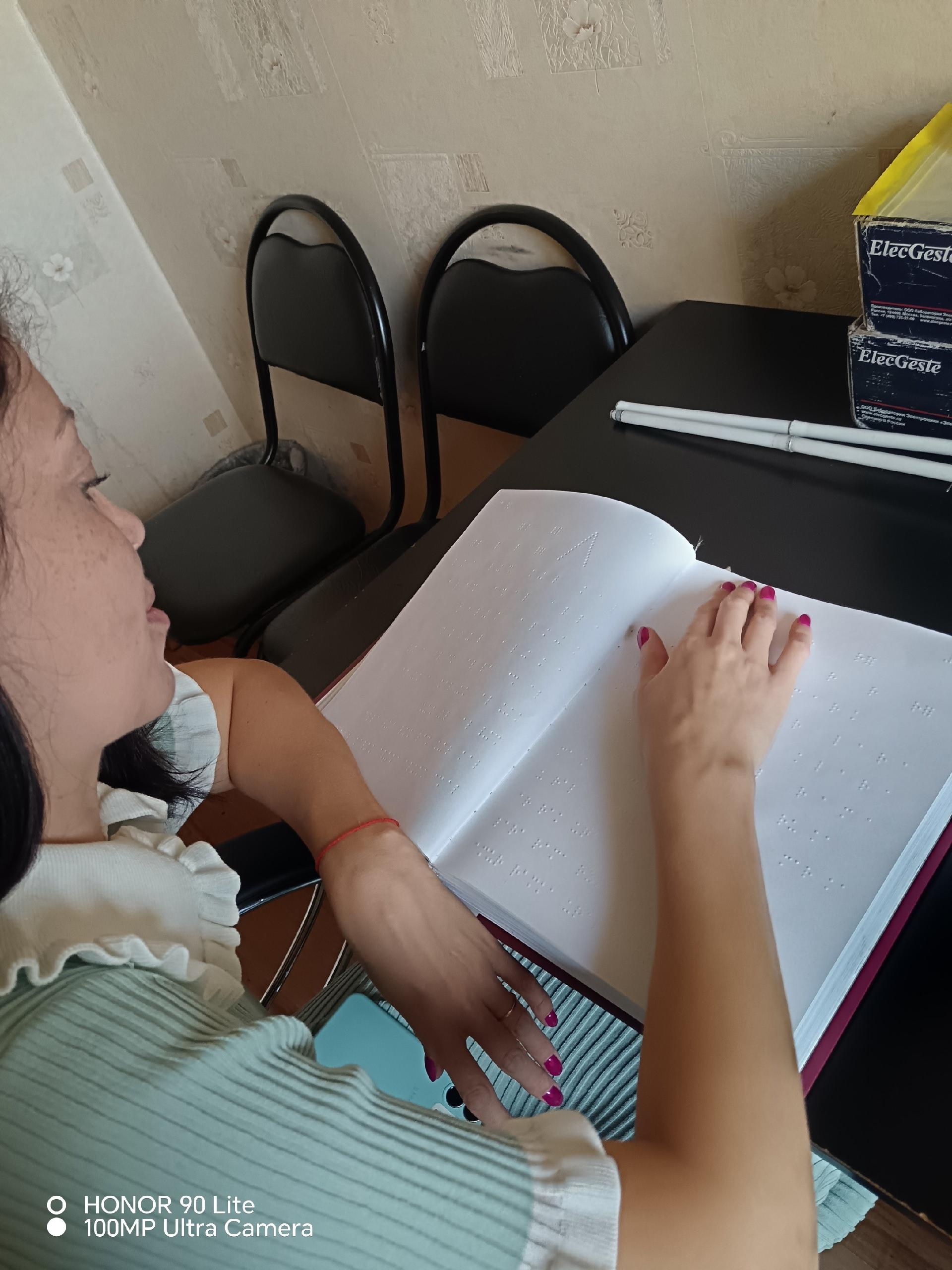 Девушка читает книгу со шрифтом Брайля пальцами рук