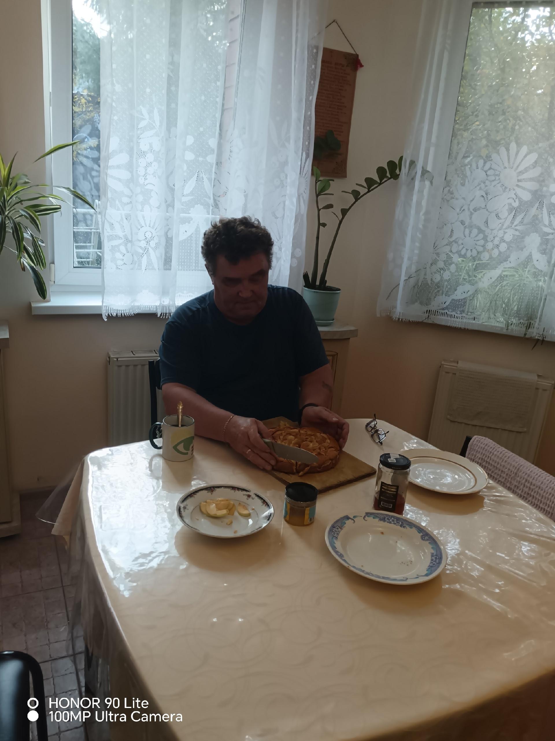 Мужчина режет готовый яблочный пирог за столом