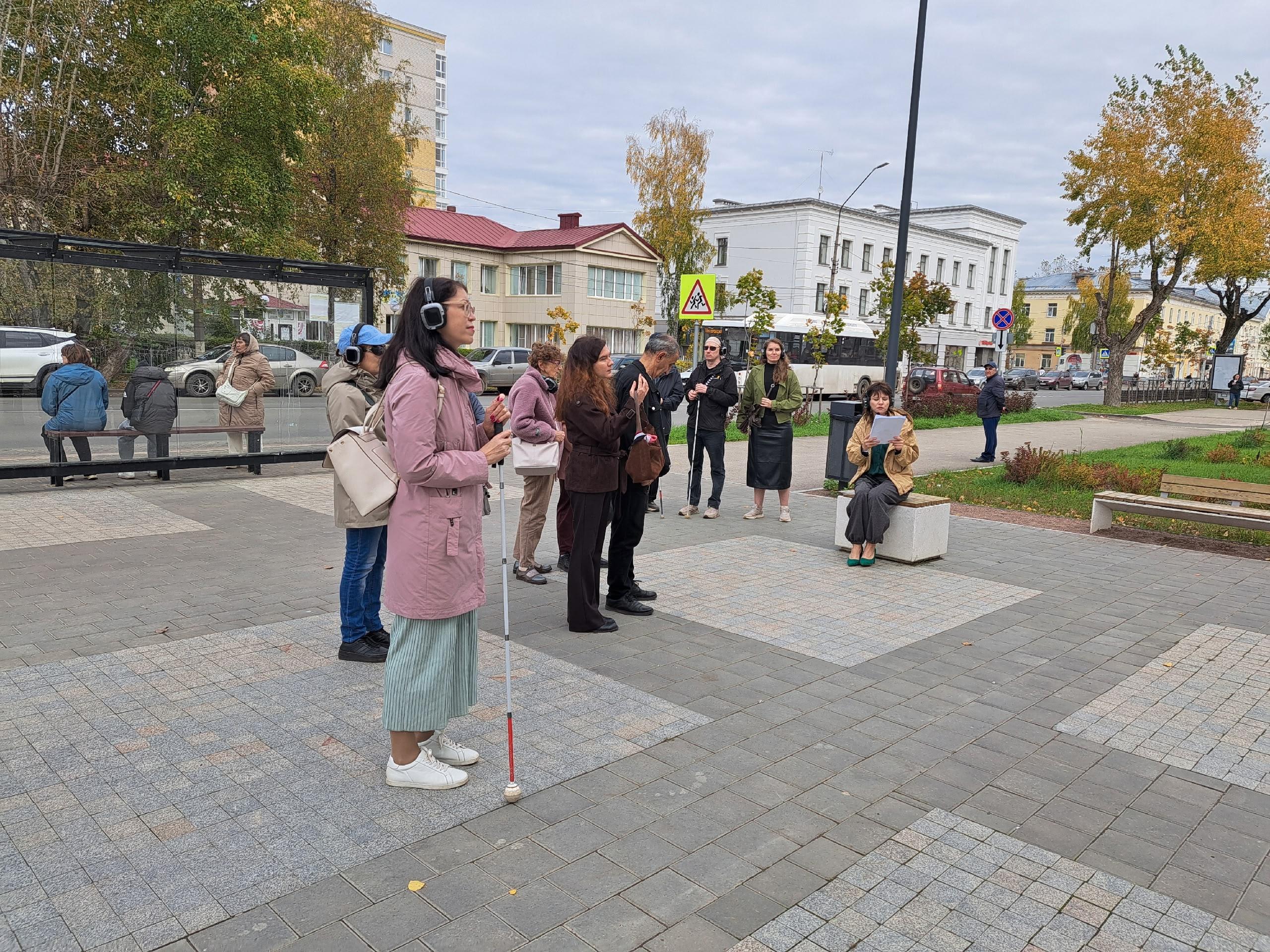 Группа участников экскурсии в наушниках на городской улице