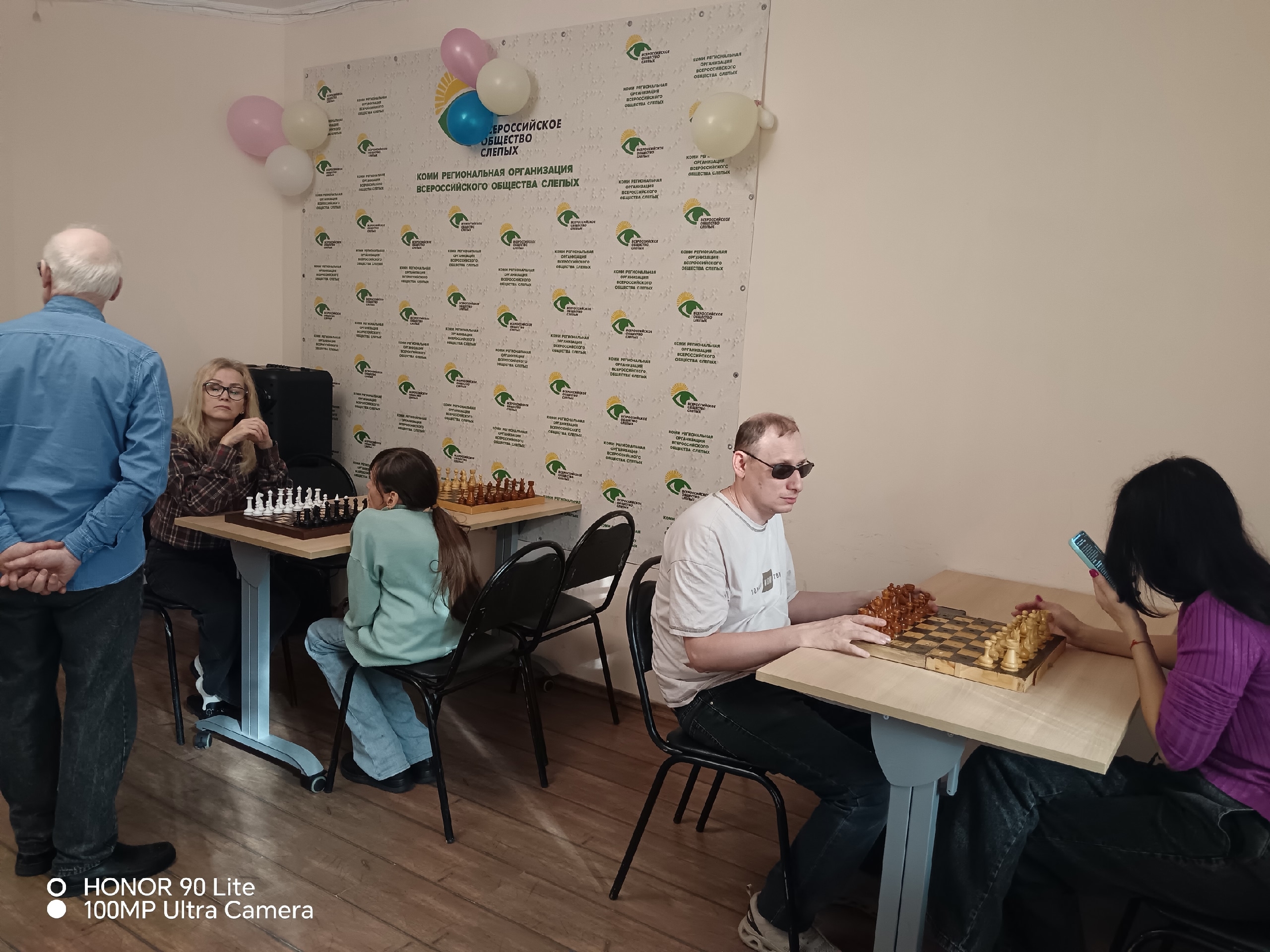 Участники шахматного занятия сидят за столами в помещении Всероссийского общества слепых