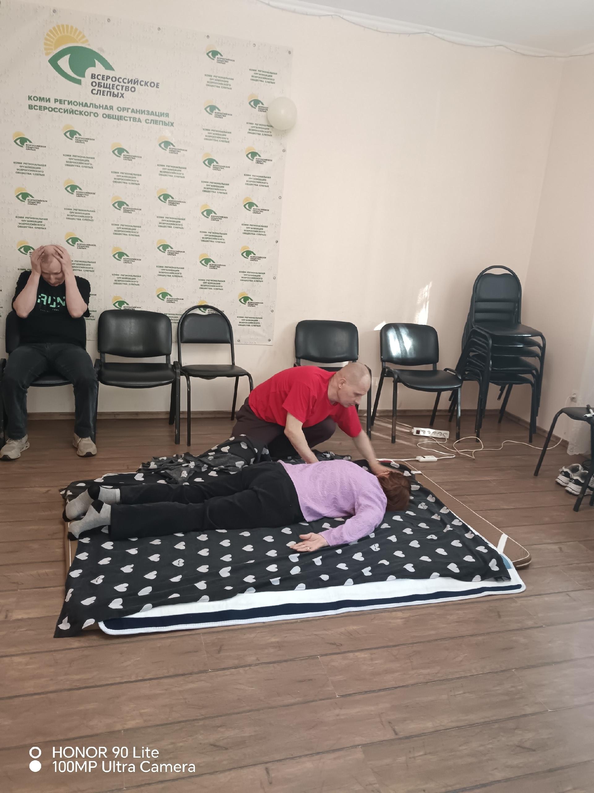 Специалист делает массаж лежащей на матрасе женщине