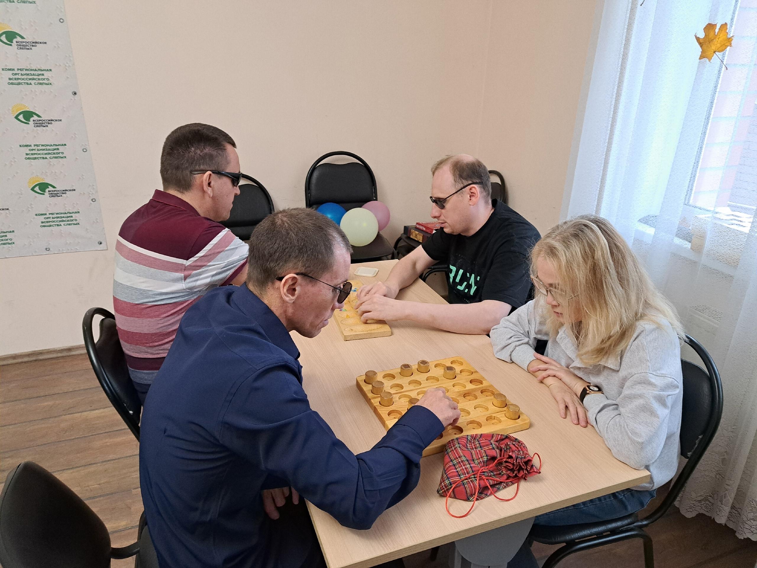 Группа людей увлеченно играет в настольные игры в помещении