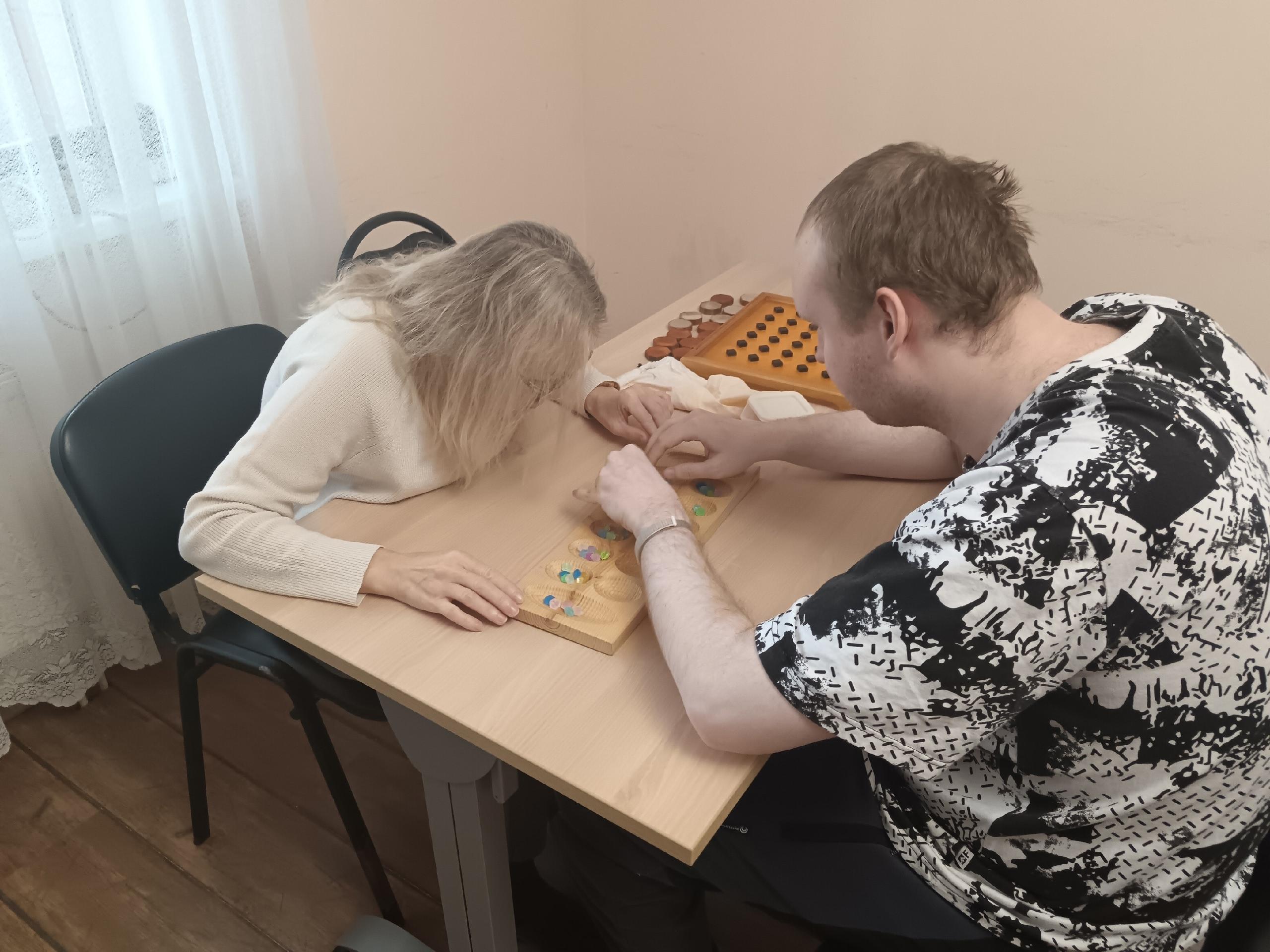 Мужчина и женщина играют в настольную игру с фишками за столом