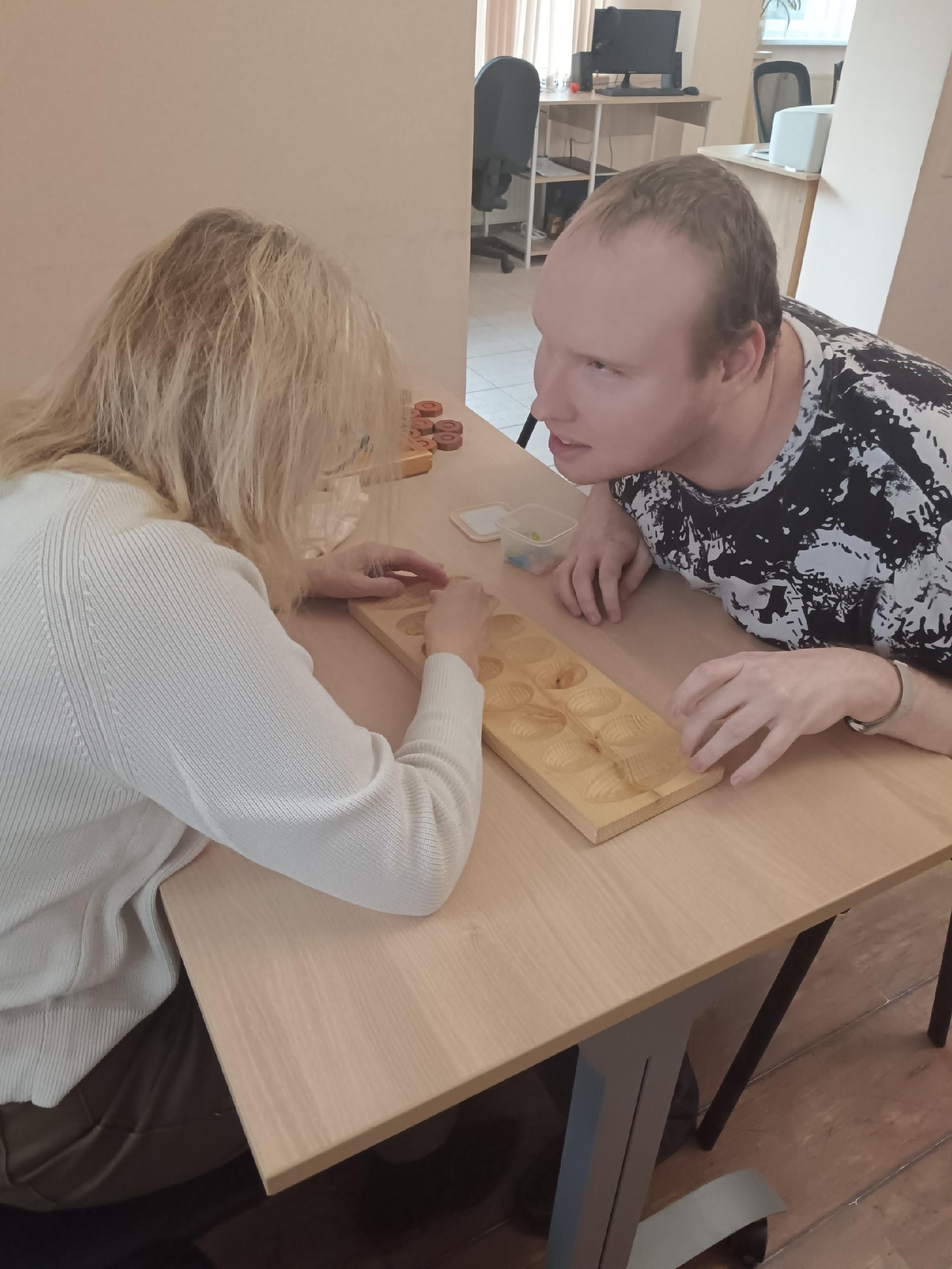 Женщина и мужчина сосредоточенно играют в деревянную настольную игру