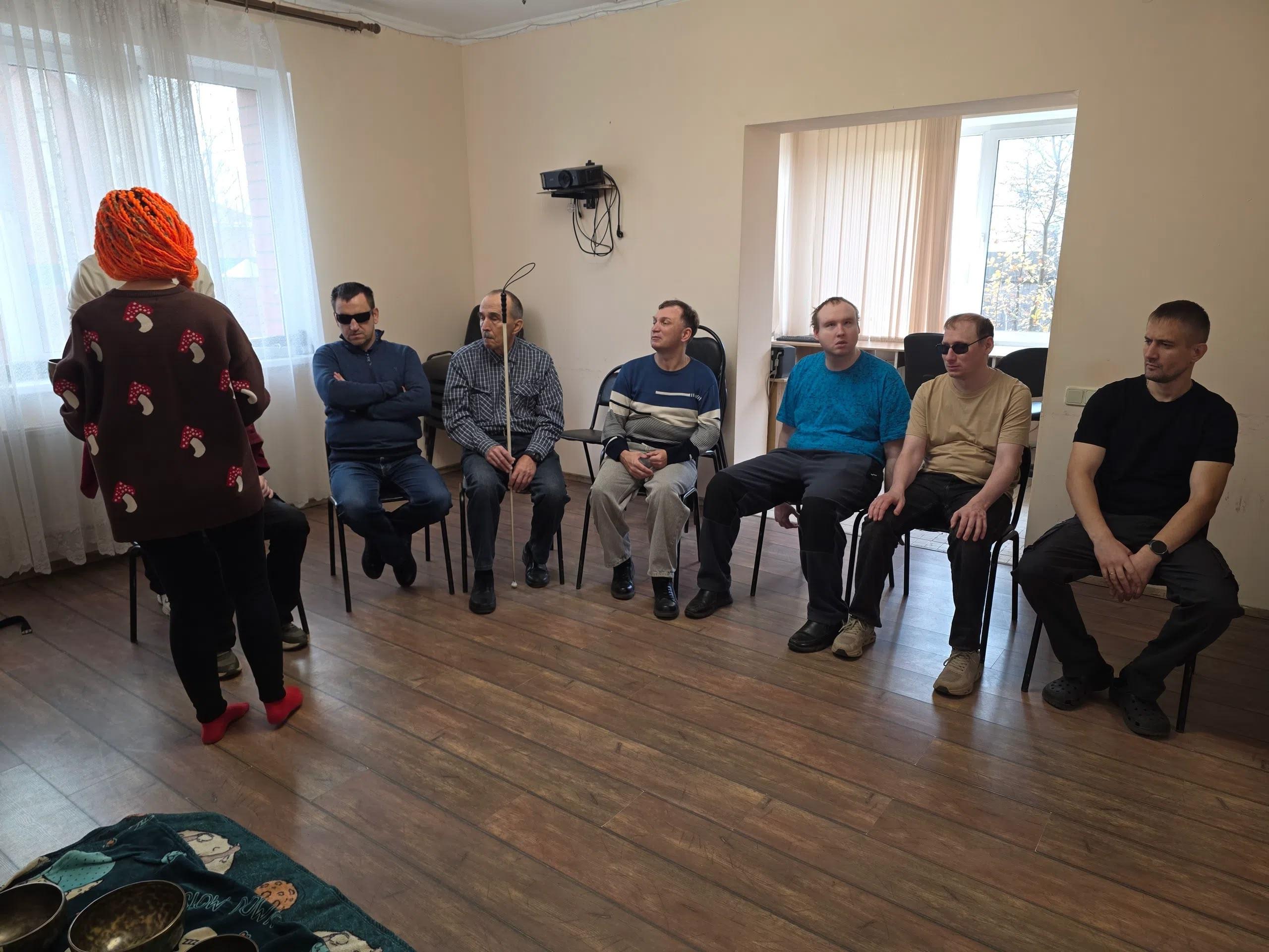 Участники Общества слепых сидят на стульях в комнате во время мастер-класса