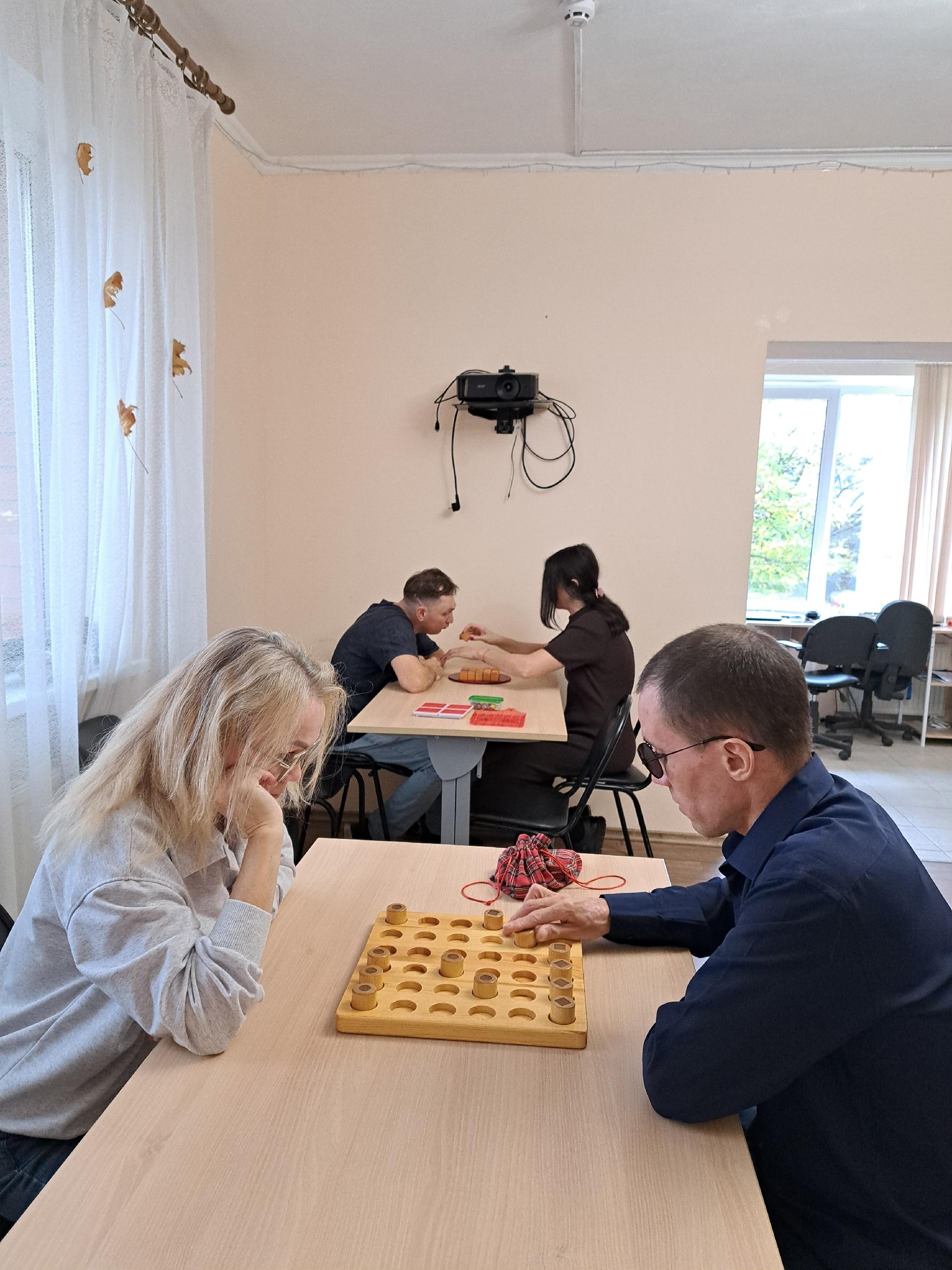 Люди сидят за столами и играют в настольные игры в помещении