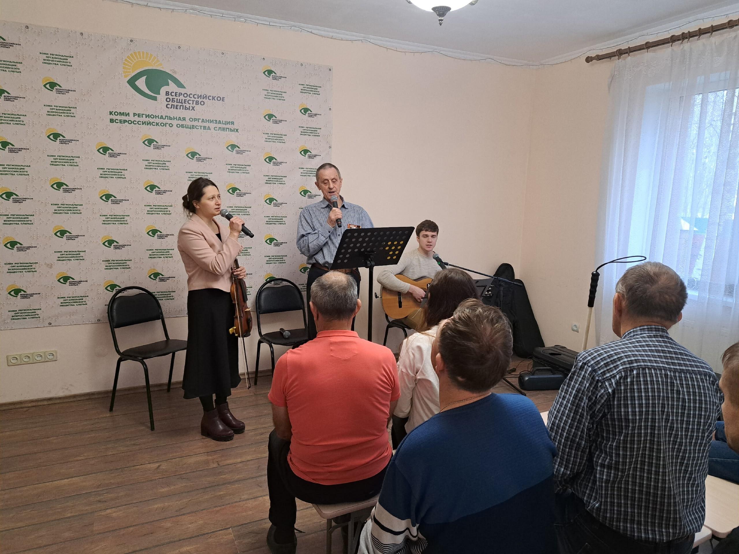 Музыкальный ансамбль выступает перед сидящими в комнате зрителями