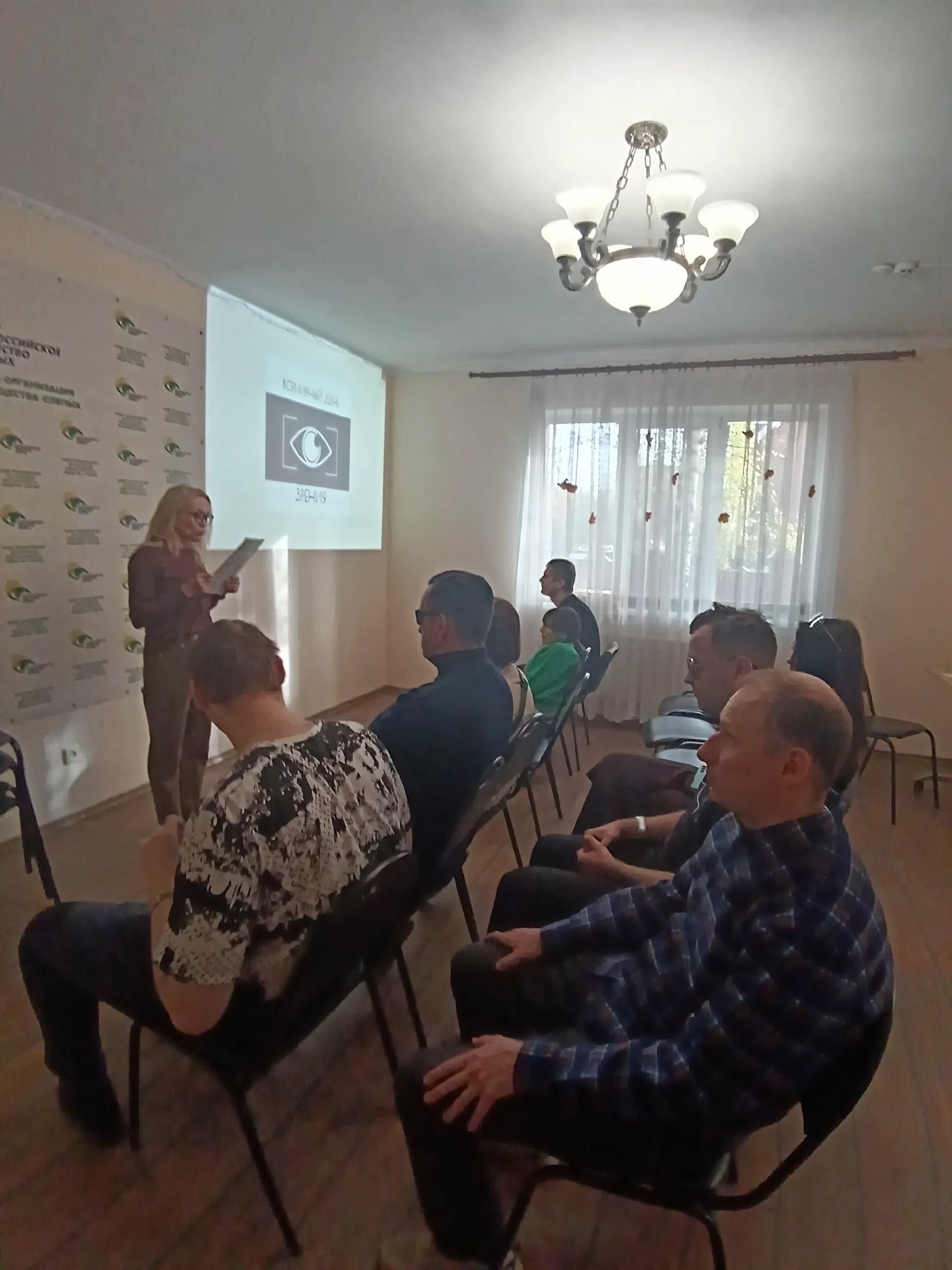 Лектор зачитывает документ на фоне проектора с логотипом