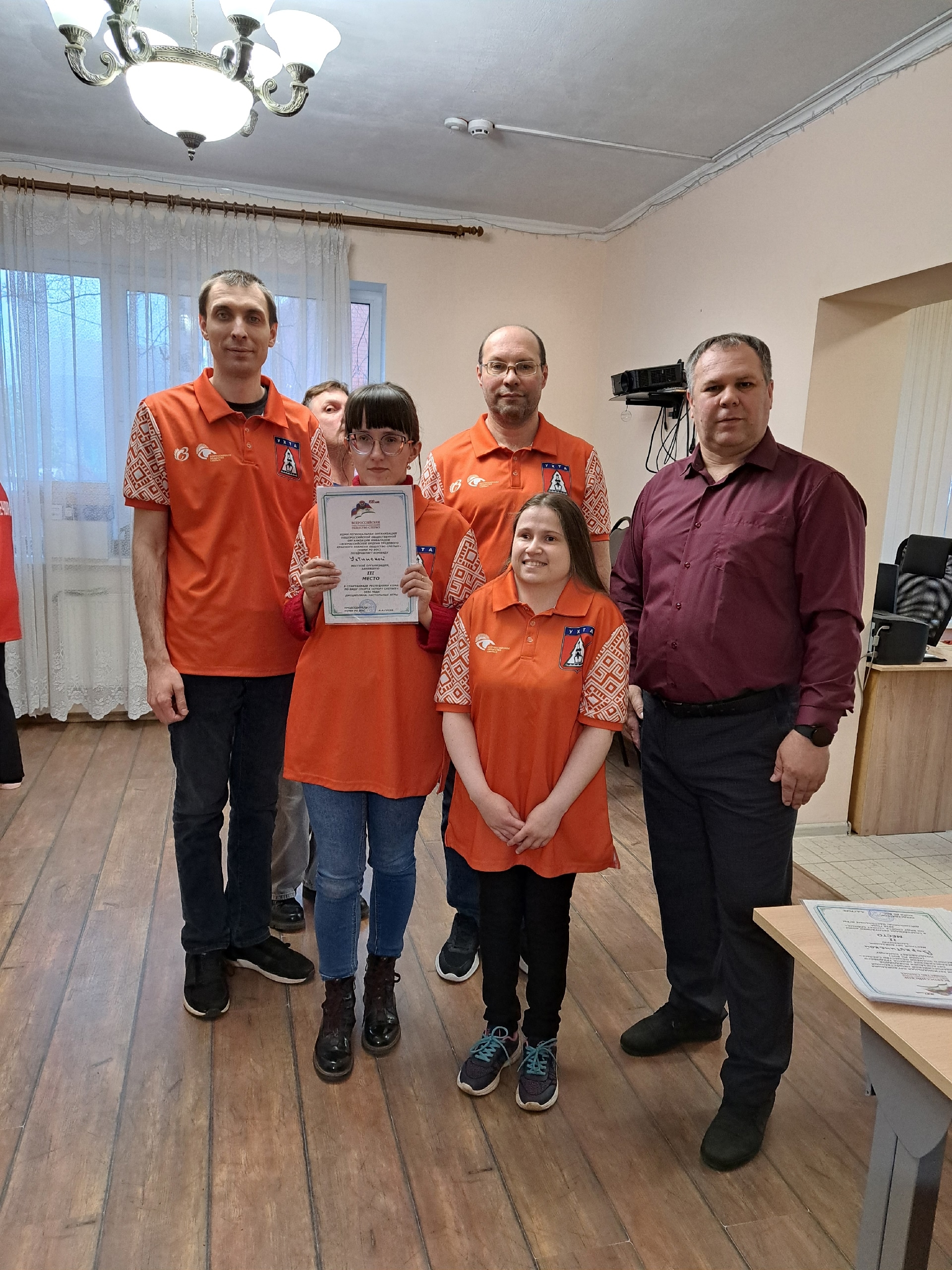 Команда в оранжевой форме демонстрирует полученный диплом